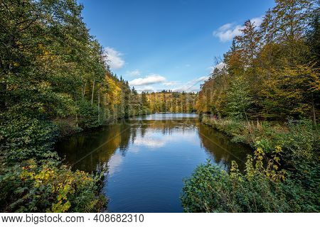 View Of A Lake In The Autumn Sunshine, Lined With Deciduous Trees, Which Produce Their Leaves In Bea