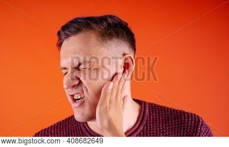 Man Getting Slapped On Orange Background. Unhappy Scared Man Getting Slapped Standing On Orange Back