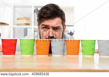 Difficult Choice. Decision-making. Serious And Sad Man With Colorful Coffee Cups. Many Cups Of Coffe