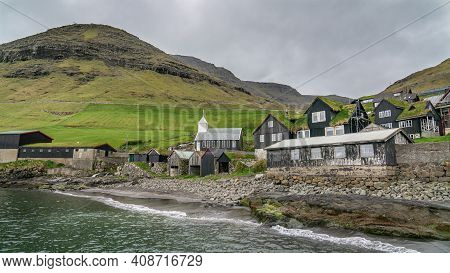 Bour, Faroe Islands - August 2019: Typical Nordic Village Overlooking A Fjord Surrounded By Green Mo