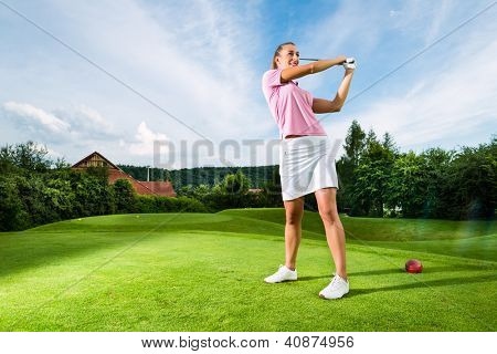 Young female golf player on course doing golf swing, she presumably does exercise