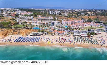 Aerial Drone Shot Of A Busy Beach, Amazing Cliffs, Vegetation And Also Buidlings In The Background. 