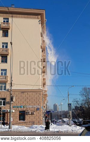 15.02.2021, Russia, Moscow. Cleaning The Roof Of The Snow. Snow Falls Against The Blue Sky.