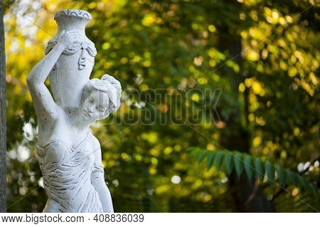 Sculpture Of A Girl In The Autumn Park. An Old Statue In A Park Of A Sensual Semi-nude Greek Or Ital