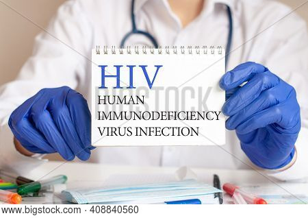 Hiv Card In Hands Of Medical Doctor. Doctor's Hands In Blue Gloves Holding A Sheet Of Paper With Tex