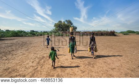 Omorate, Ethiopia - September 2017: Unidentified Woman From Dassanech Tribe Carrying Water To Her Vi