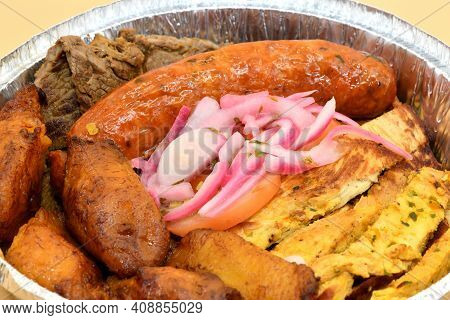 A Columbian Meat Plater Made Of Sausage, Steak, Chicken, Plantains, And Pickled Onions.