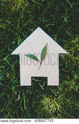 Green Home And Eco-friendly Construction, House Icon On Green Grass Lawn Under The Sun With Two Leav