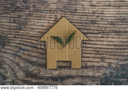 Green Home And Energy Efficiency, Ecological House Icon With Leaves On It On Wooden Background