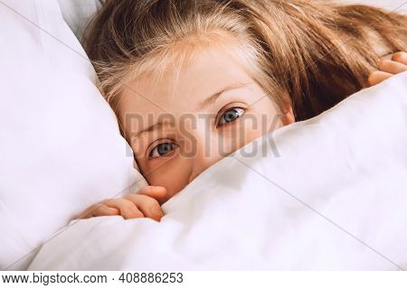 Child Hiding Under Duvet In Bed. Morning Routine. Indulge In The Bedroom In The Morning. Girl In Bed