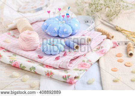 Sewing tools and supplies  - handmade pincushion, scissors, bobbins with thread, needles and fabric. Hobby, crafting, creativity, free time at home concept.