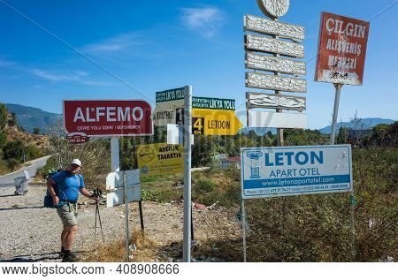 Kumluova, Turkey - 10 October, 2019: Signs on Lycian way hiking trail, Man tourist standing next to many different shape sign boards, directions indicators, arrows, advertising signs