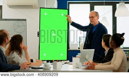 Mature Businessman Analysing Annual Financial Reports Standing In Conference Room Pointing At Green 