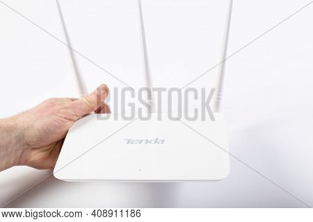 White Wifi Router Tenda With Three Antennas In Hand, On White Background.