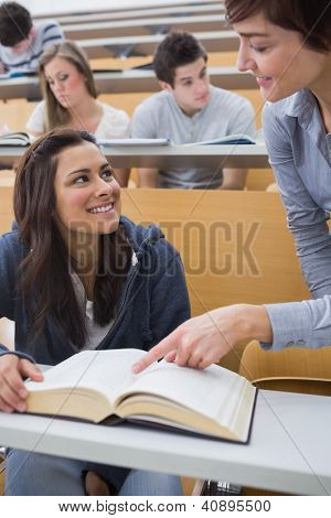 Explainging de profesor a estudiante en la sala de conferencias con libro grande