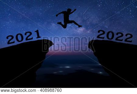 A Young Man Jump Between 2021 And 2022 Years Over Night Sky With Stars And Through On The Gap Of Hil
