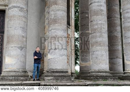 A Man Outsized By Huge Pillars Of An Ancient Structure.