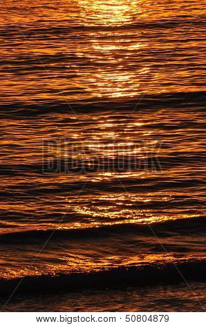 The reflection of the setting sun on the waves in the ocean