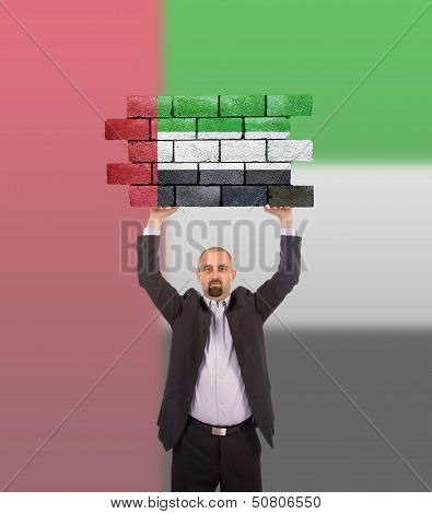 Businessman Holding A Large Piece Of A Brick Wall