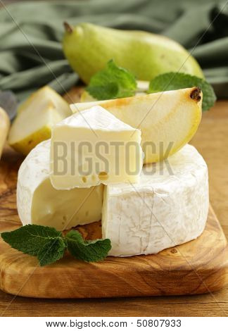 soft brie cheese (camembert) with pears on a wooden board