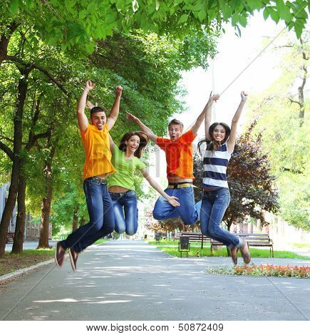 Happy group of young people jumping in park