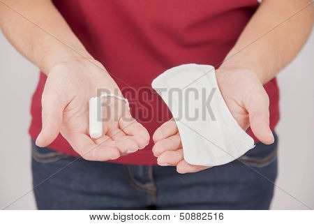 Young woman choosing between pad and tampon