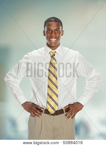 Young African American businessman with hands akimbo inside office building