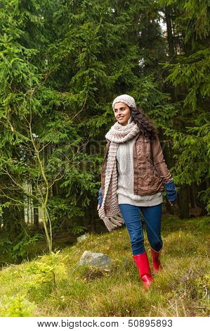 Woman walking in pinewood autumn wear knitted scarf and hat