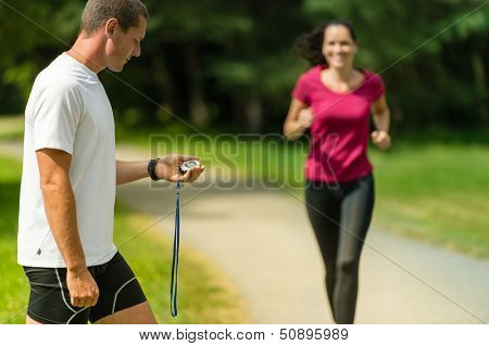 Portrait of male coach timing runner in a park