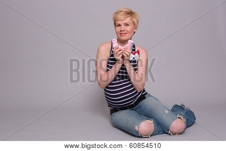 Happy Young Pregnant Woman Holds A Pink Socks For His Daughter