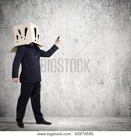 Businessman using mobile phone wearing carton box on head