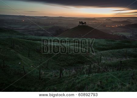Beautiful Sunrise Dawn Landscape Of Hills Overlooking Brightly Lit Town In Valley Below