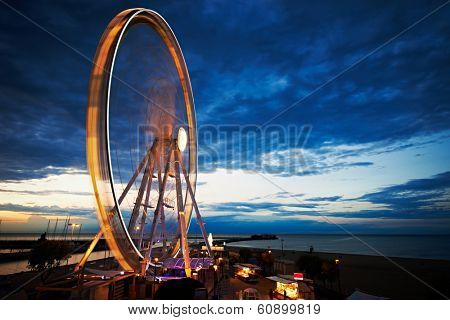 Amusement park at night - ferris wheel and rollercoaster in motion