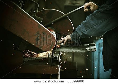 Industrial worker cutting and welding metal with many sharp sparks