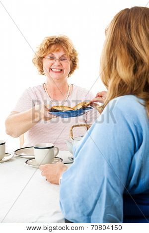 Two mature ladies having a tea party together.  White background