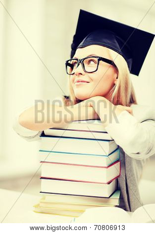 business and education concept - happy student in graduation cap with stack of books