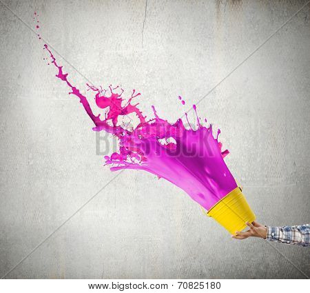 Close up of hand splashing colorful paint from bucket