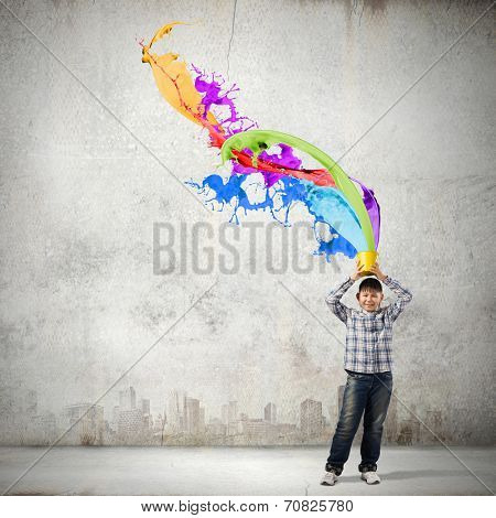 Young boy splashing colorful paint from bucket