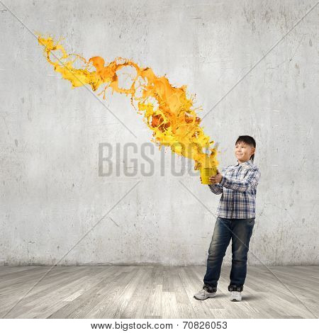 Young boy splashing colorful paint from bucket