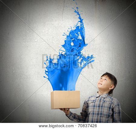 Young boy splashing colorful paint from carton box