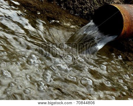 stream of artesian water from the old rusty pipe