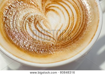 Cappuchino or latte coffe in a white cup with heart shaped foam