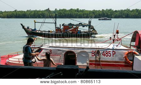 PULAU KETAM, MALAYSIA - JANUARY 18, 2015: Passengers board the ferry boat at a jetty at the fisherman's wharf in Pulau Ketam (Crab Island). This island is famous for sea food products and restaurants.