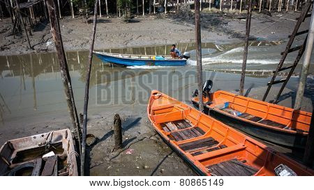 PULAU KETAM, MALAYSIA - JANUARY 18, 2015: A speed boats passes by the fishermen village on Pulau Ketam (Crab Island) after return from sea. This island is famous for sea food products and restaurants.