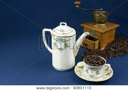 coffee mug on the table with a blue tablecloth, poured out coffee beans