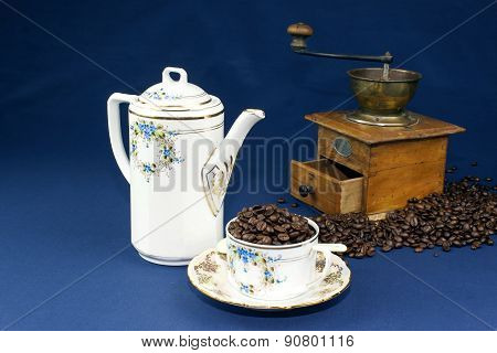 coffee mug on the table with a blue tablecloth, poured out coffee beans