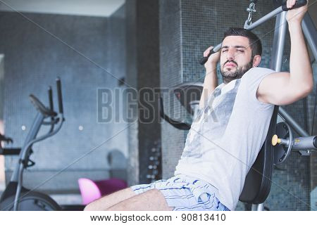 Man using pull down machine in gymnasium.Handsome muscular man exercising on pull down machine