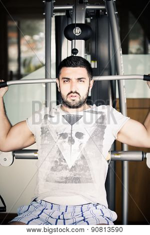 Man using pull down machine in gymnasium.Handsome muscular man exercising on pull down machine