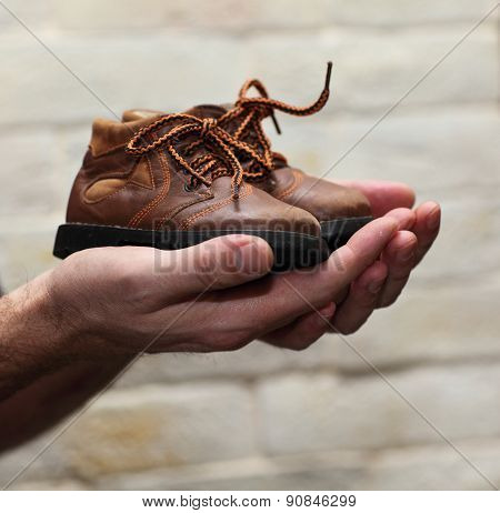 Dirty hands holding a pair of old childrens shoes