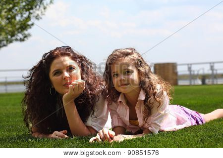 Young mother and daughter laying on the grass